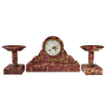 Garniture de cheminée en marbre rouge veiné : pendule centrale et deux coupes assorties, vue de face sur fond transparent.