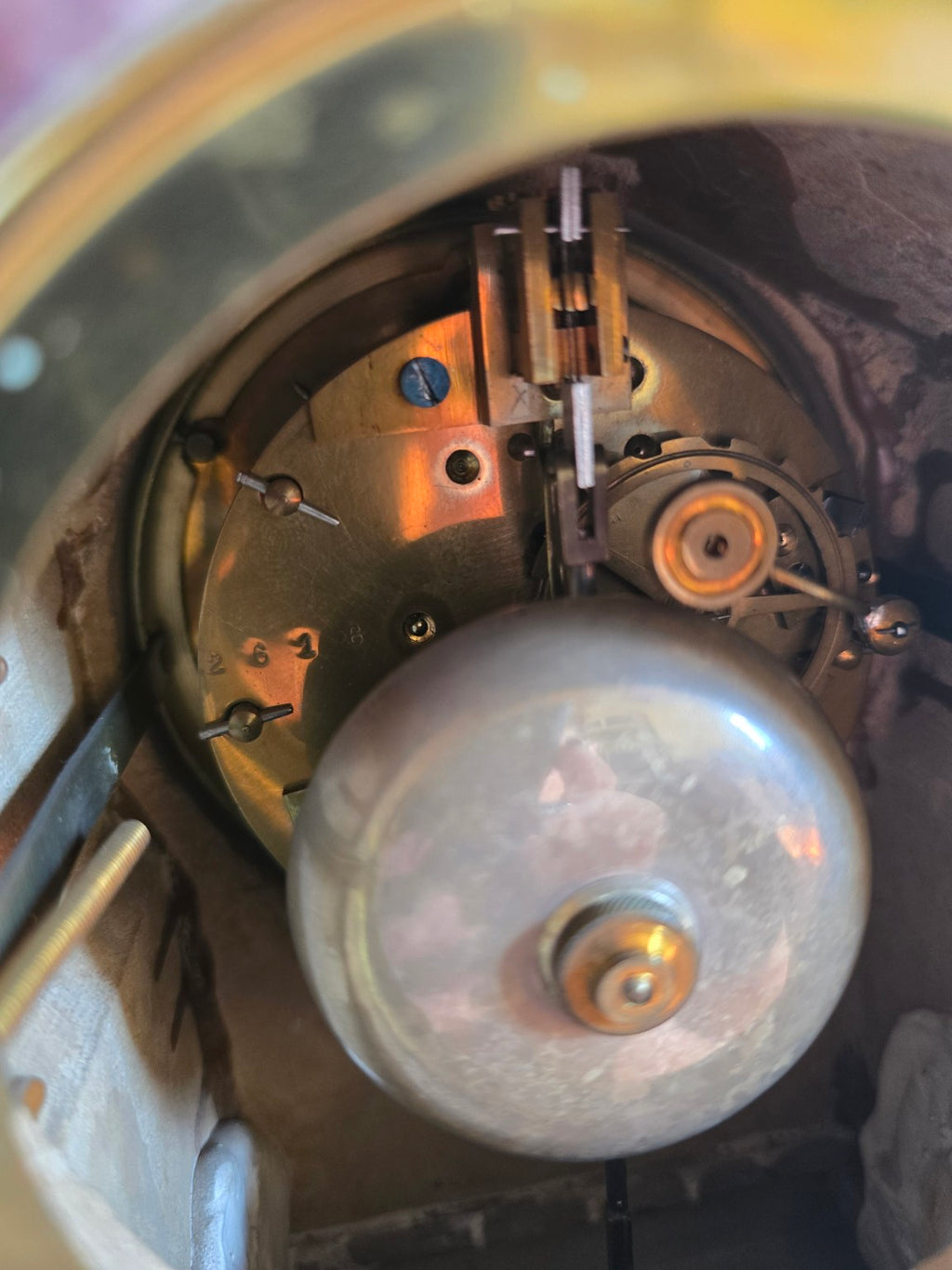 Détail du mouvement à balancier et du timbre métallique à l’intérieur de la pendule.