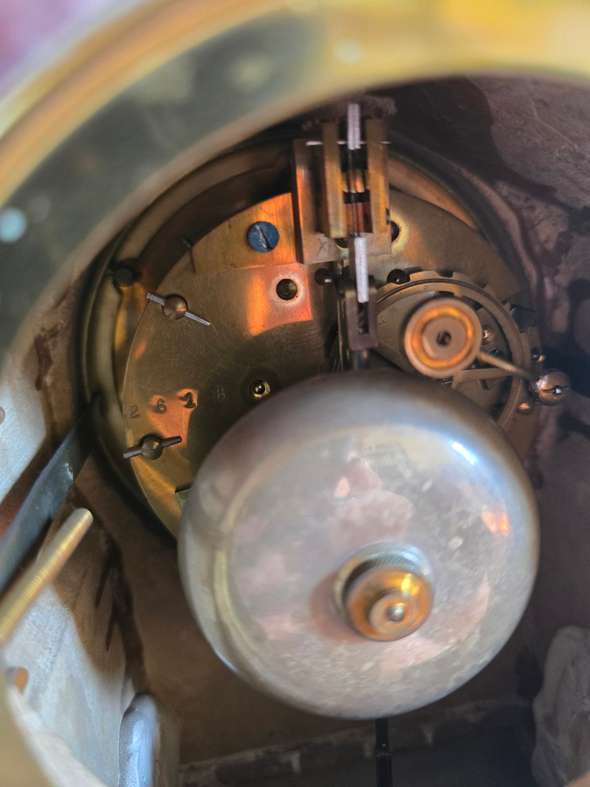 Détail du mouvement à balancier et du timbre métallique à l’intérieur de la pendule.