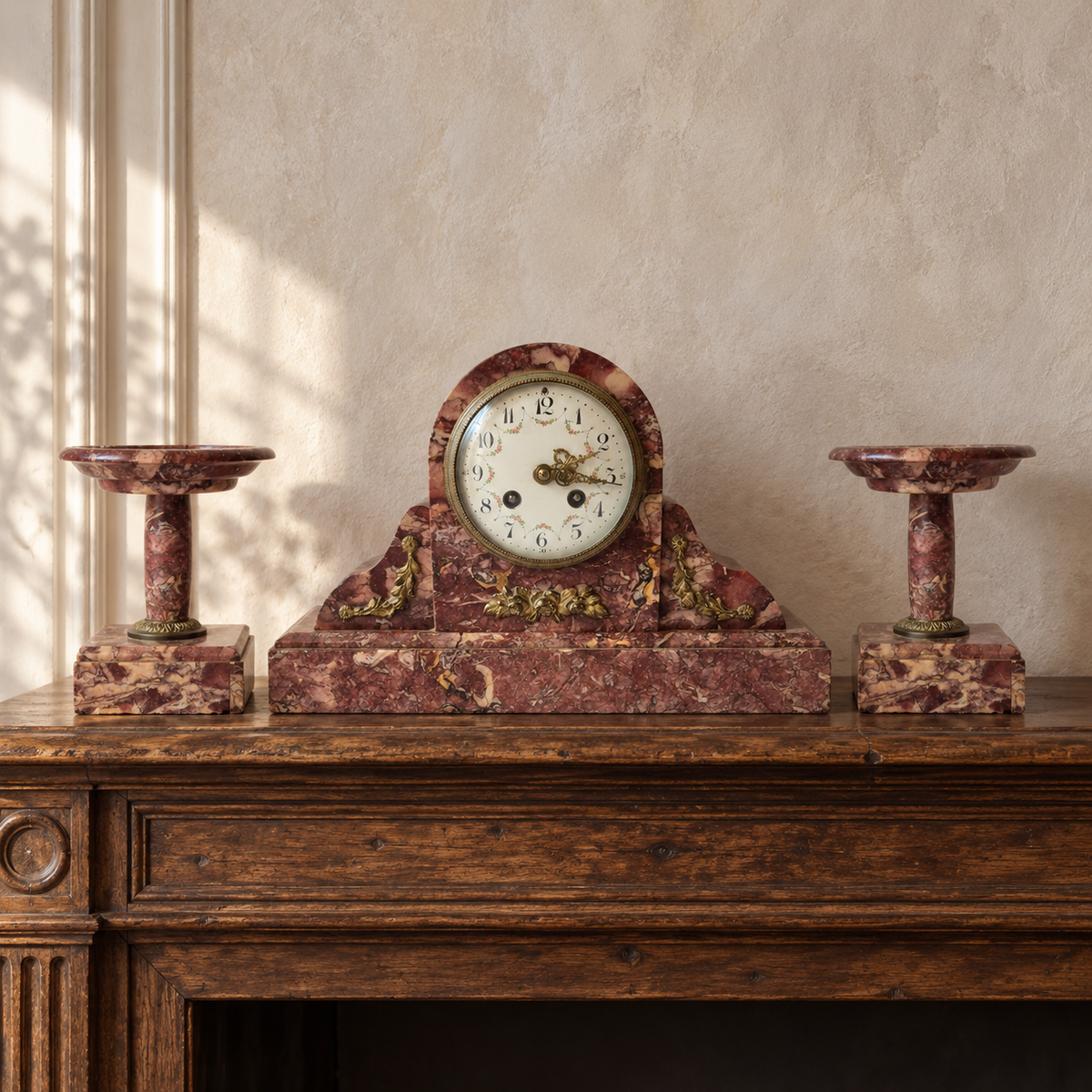 Pendule en marbre rouge et deux coupes assorties en situation sur une console, dans une ambiance beige douce.