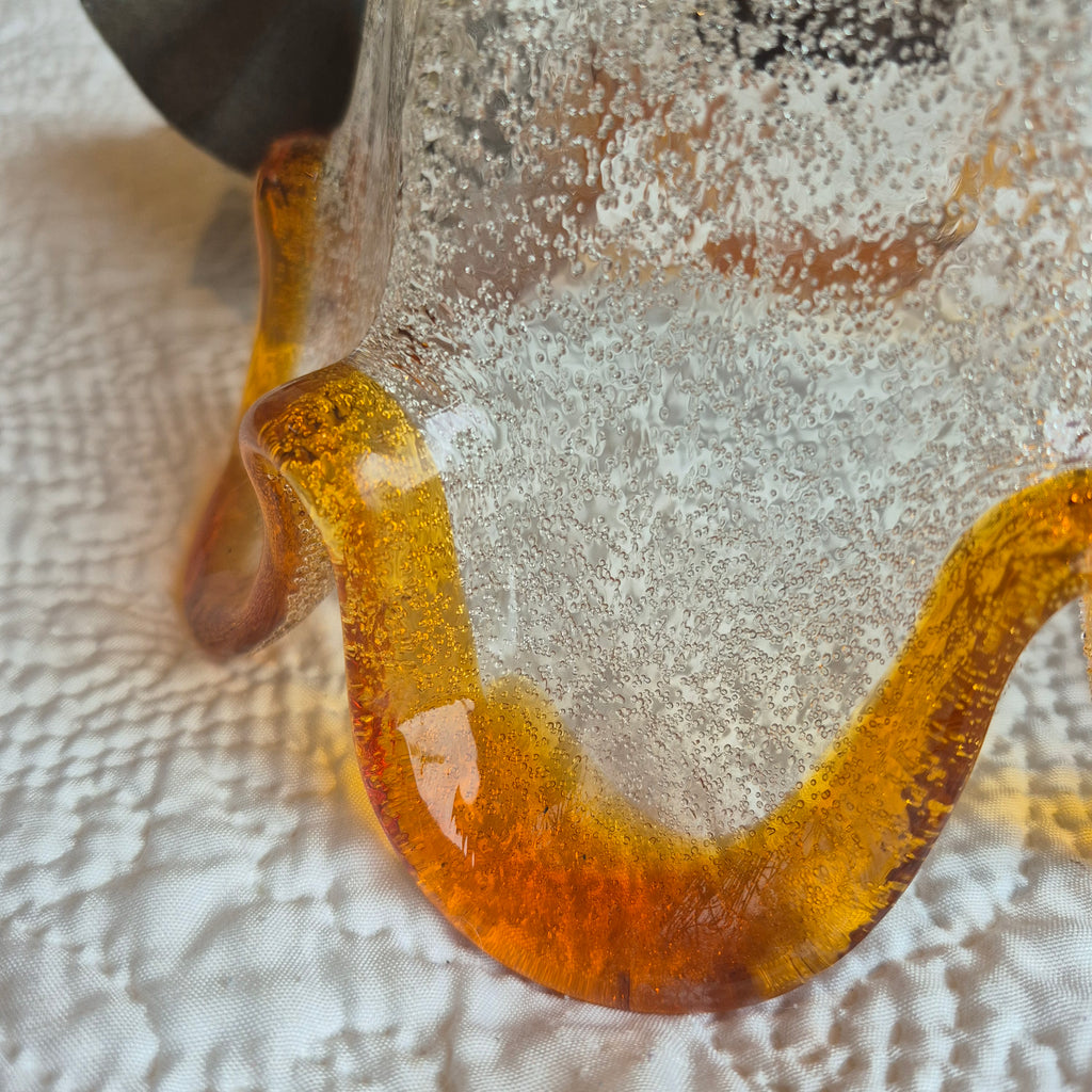 Gros plan sur le verre texturé et la bordure ambrée ondulée de la suspension fleur